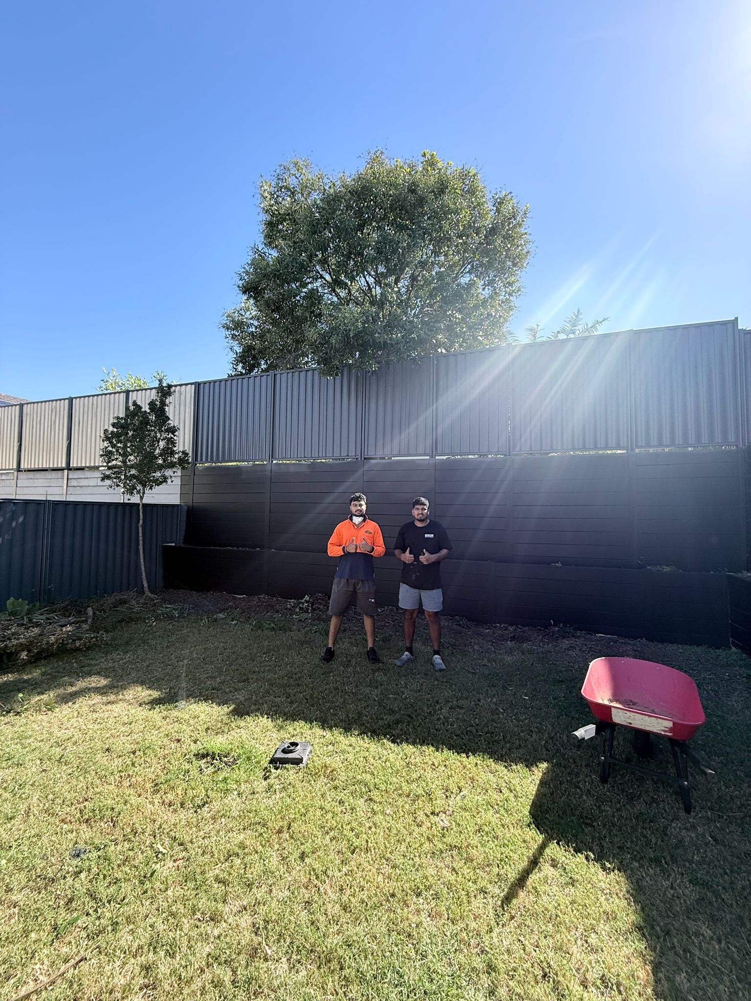 Completed fence painting job — Paintmates team with finished dark charcoal fence